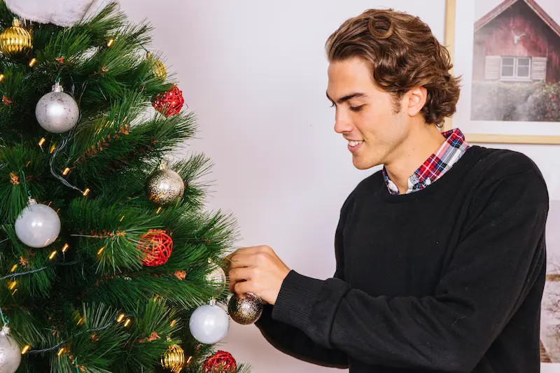hombre-sonriente-decorando-arbol-de-navidad